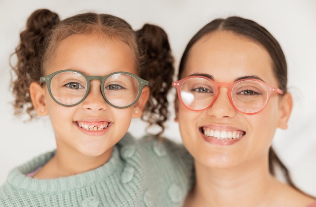 A child and adult smiling, both wearing a new pair of glasses they got from their optometrist