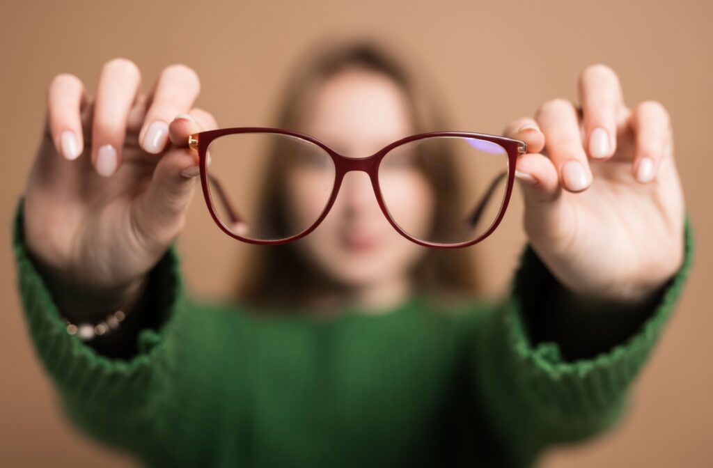 A person holding out a pair of glasses in front of their face.